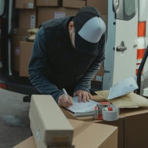 Courier organizing packages from a van, preparing for delivery in a logistics setting.